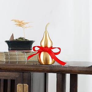 Feng Shui decor statue of a Wu Lou brass gourd with a red luck strip.